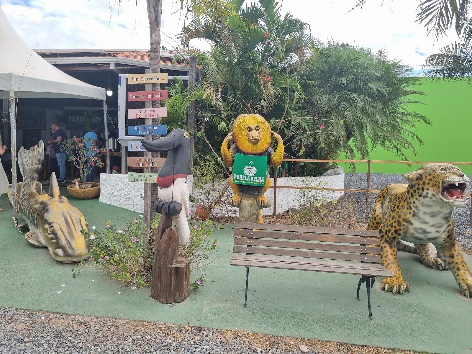 Entrada do restaurante com estátuas de onça e mico-leão e a placa Panela Velha